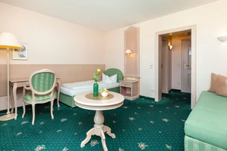 Zimmer in grün gehalten mit Bett, Sofa und Schreibtisch