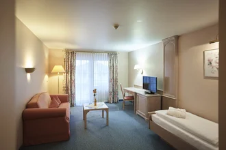 Einzelbett Zimmer mit Sofa, Fernseher und Schreibtisch